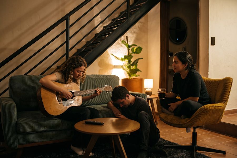 Un jam en el Tiny Room: alguien tocando la guitarra en el sofá y dos personas escuchando