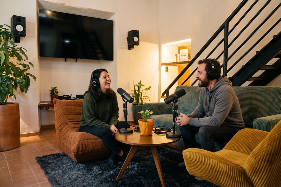 Dos personas grabando un podcast con micrófonos sobre la mesita del Tiny Room