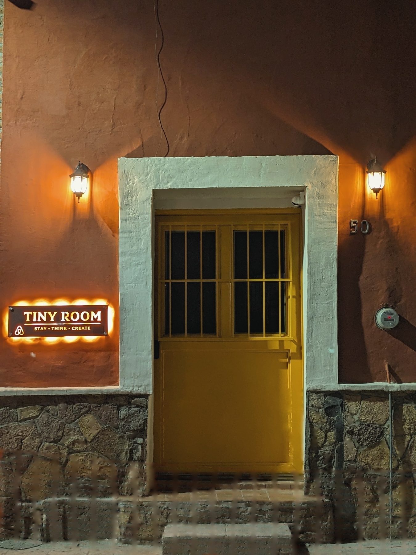 La puerta amarilla del Tiny Room, con su letrero iluminado, en el centro histórico de Hermosillo